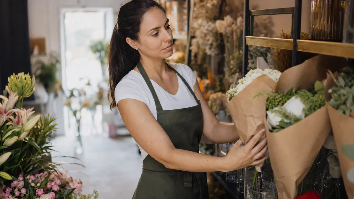 Flower shop owner preparing an AI reply generator response before arranging customer bouquets.