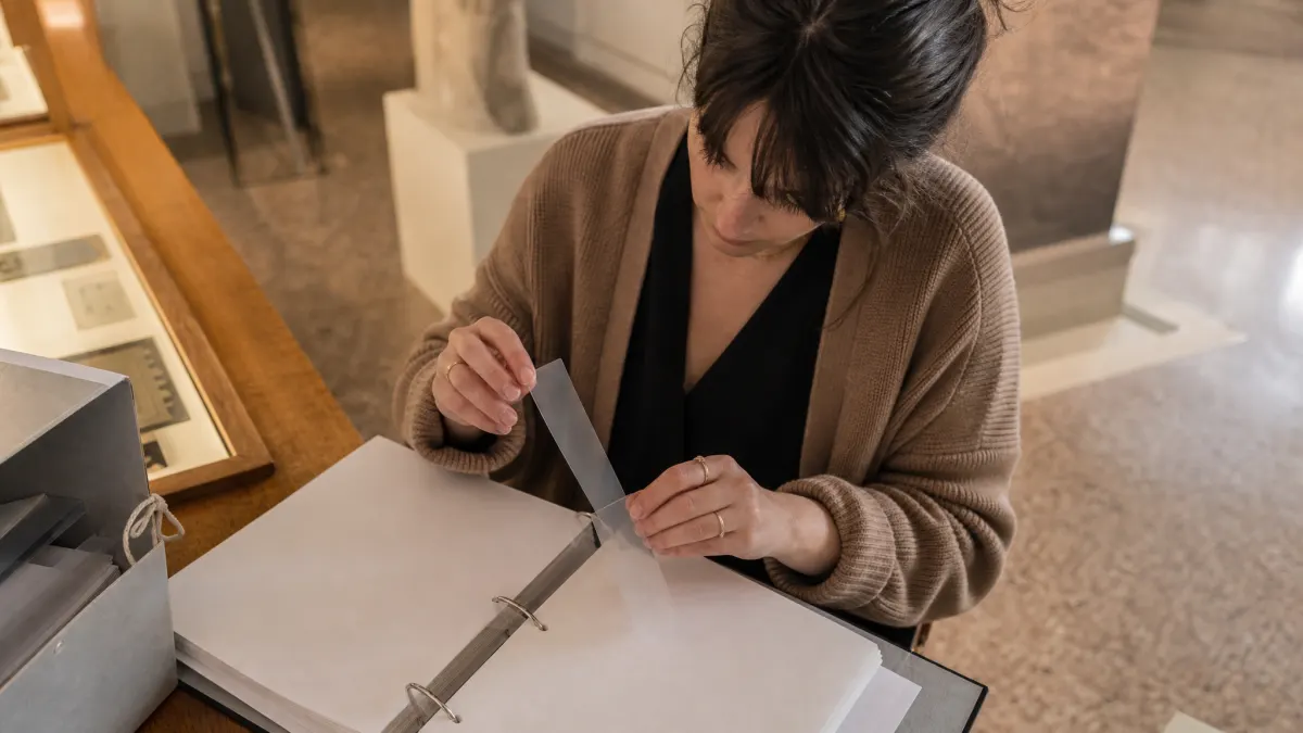 Graduate student organizes chat with PDF prompts in a quiet museum research alcove.