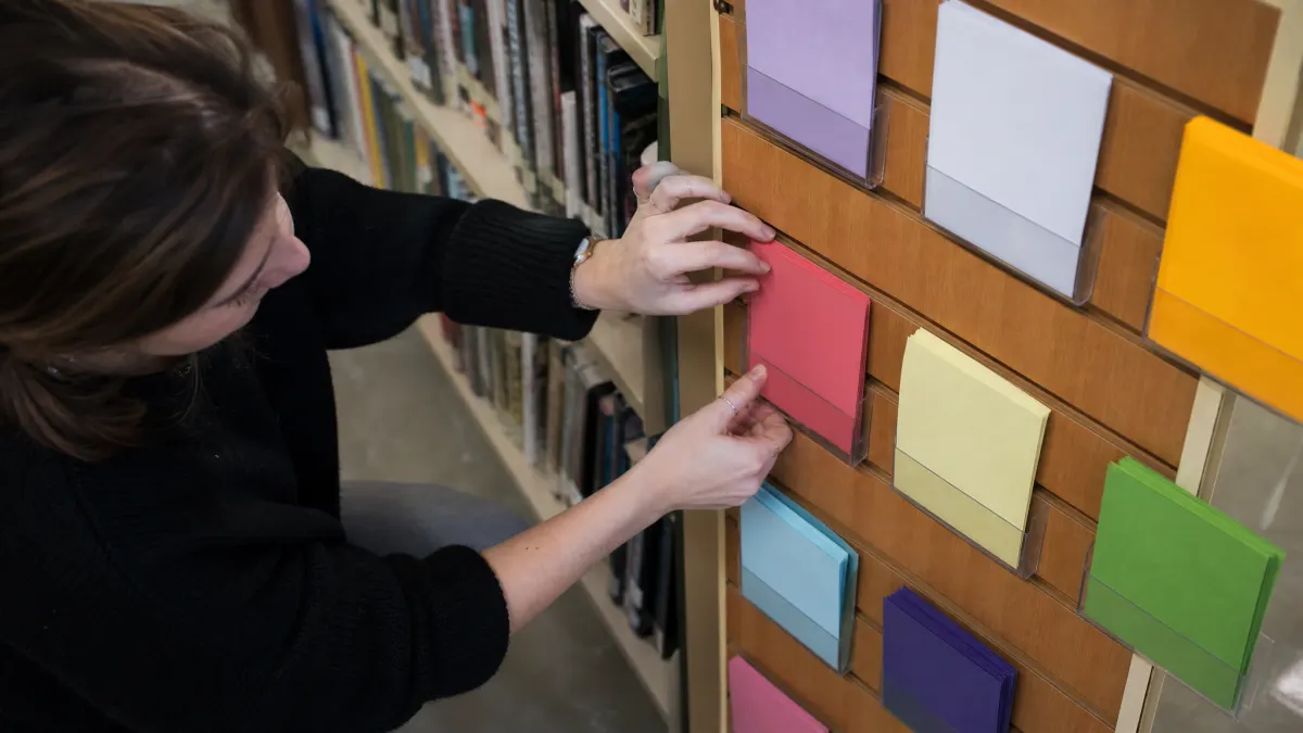 Graduate student arranges blank intent cards for a keyword clustering tool in a library.